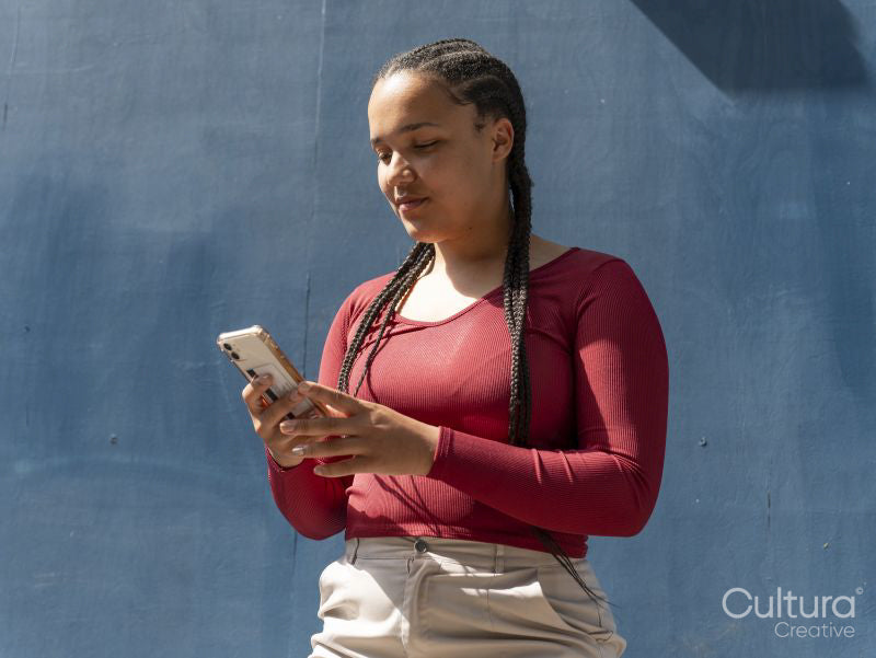 Young woman using smart phone against blue wall
