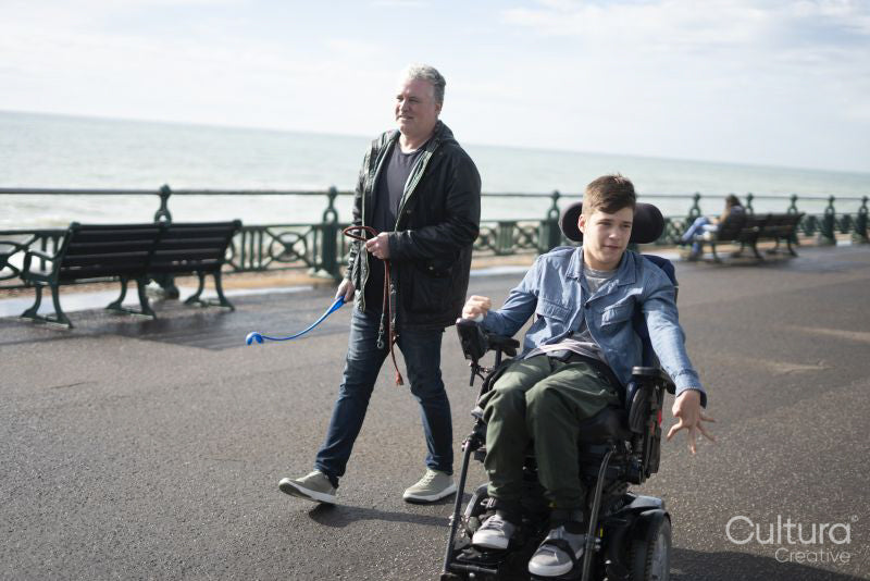 Father and disabled son strolling on promenade