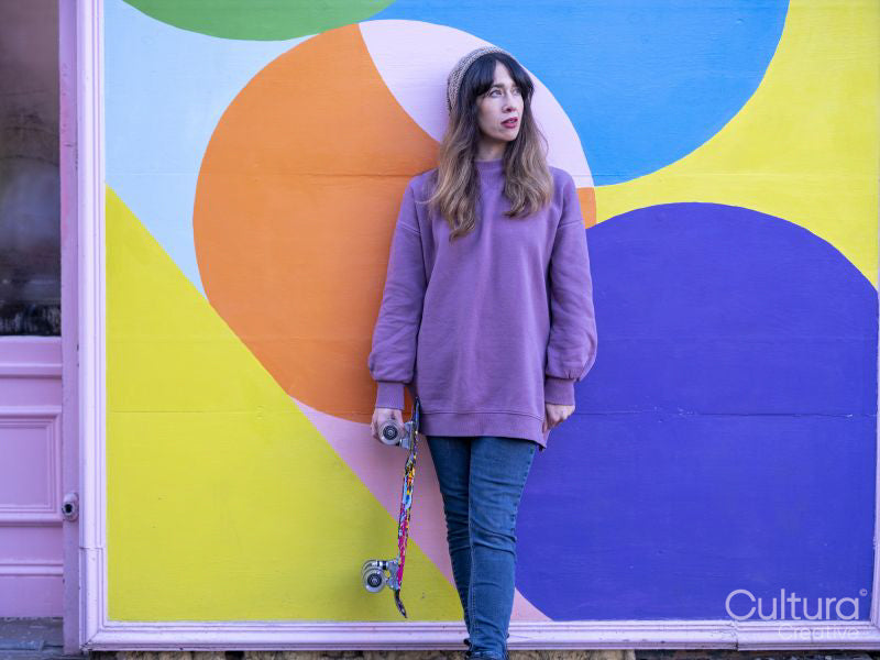 Portrait of woman standing with skateboard against multi colored wall