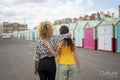 Female couple strolling by beach huts