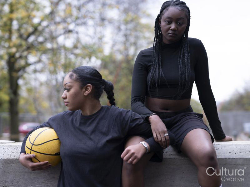 Two female friends outdoors holding basketball ball