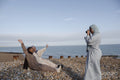 Woman photographing Muslim friends on beach