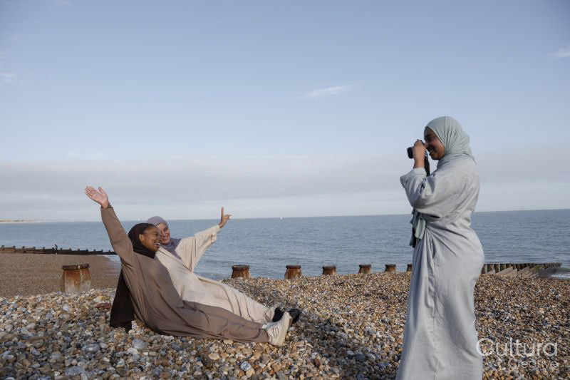 Woman photographing Muslim friends on beach