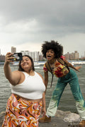 Two women taking pictures by river