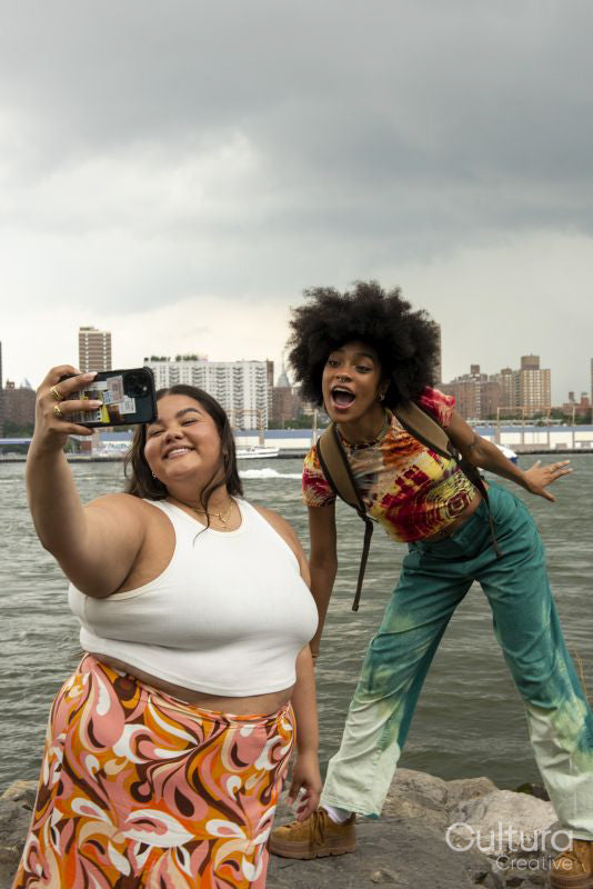 Two women taking pictures by river