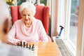 Senior woman playing chess in nursing home