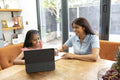 Smiling mother and daughter using digital tablet at home