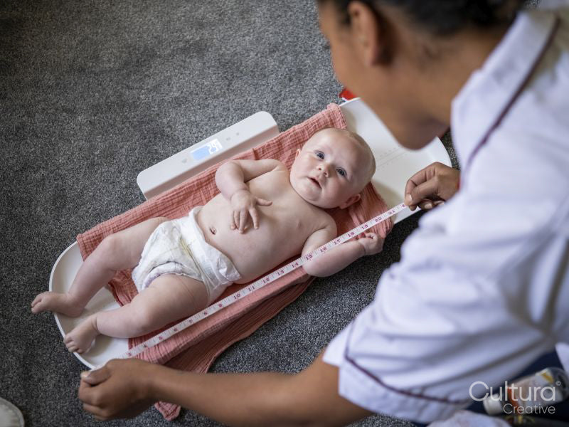 Nurse taking growth measurements of baby girl