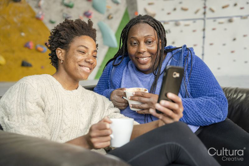 Mother and daughter looking at smart phone after training on climbing wall