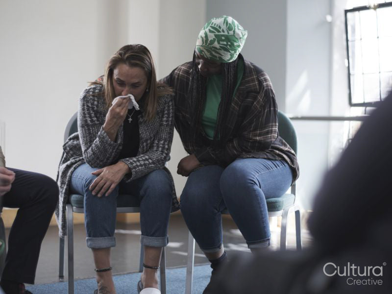 Woman consoling crying woman in group therapy session