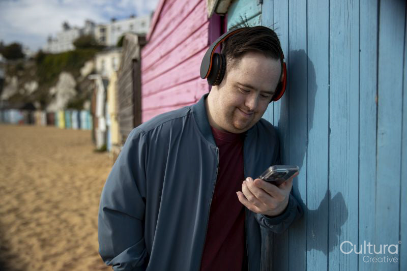 Mid adult man wearing headphones, holding smartphone