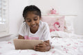 Smiling girl lying on bed with tablet
