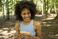 Young woman eating snack in forest