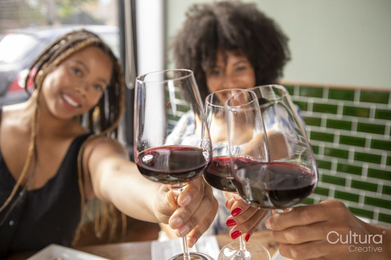 Close-up of friends toasting with red wine at restaurant table