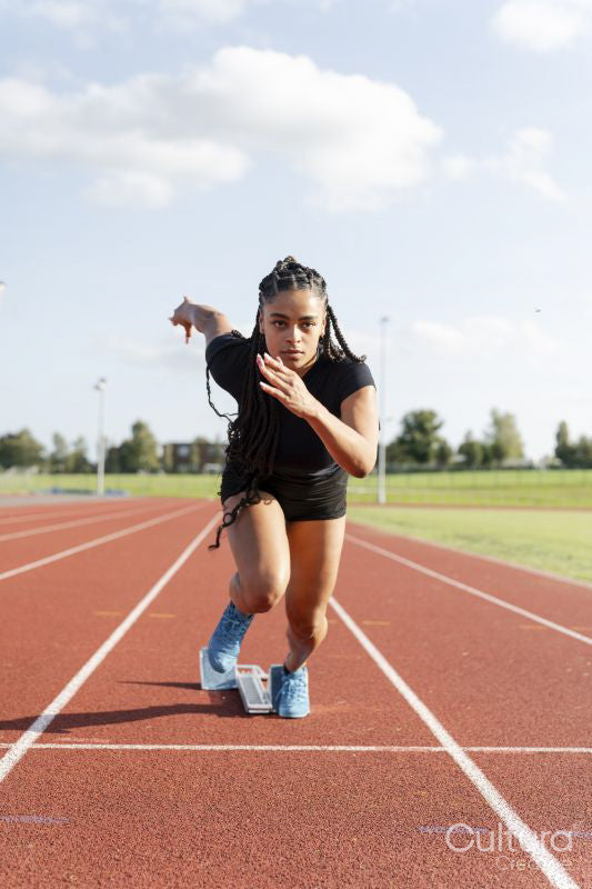 Female athlete sprinting off starting line at stadium