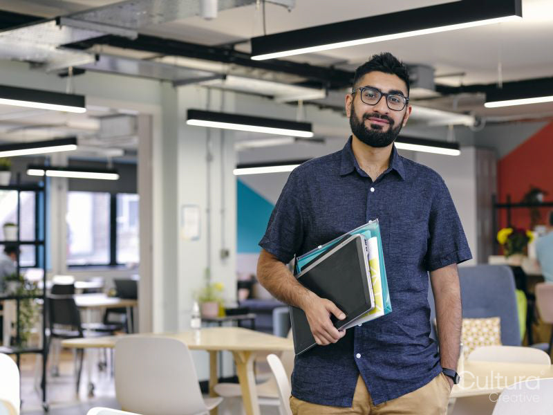 Portrait of man holding laptop in office