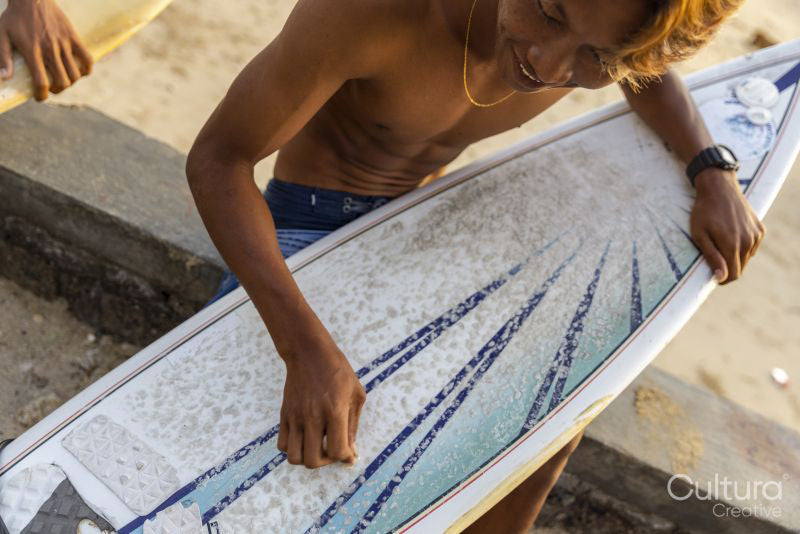 Surfers preparing surfboards on beach