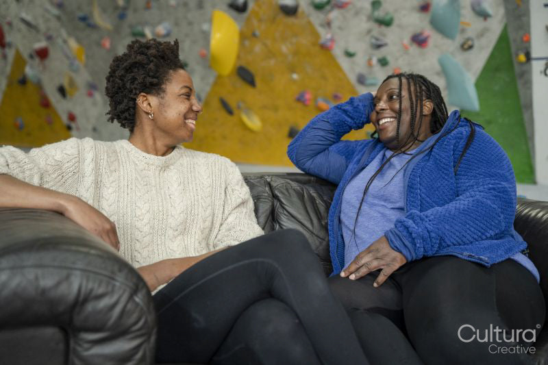 Mother and daughter sitting on sofa in front of climbing wall