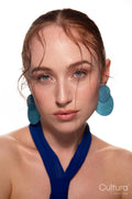 Studio portrait of a woman in a blue dress and large blue earrings
