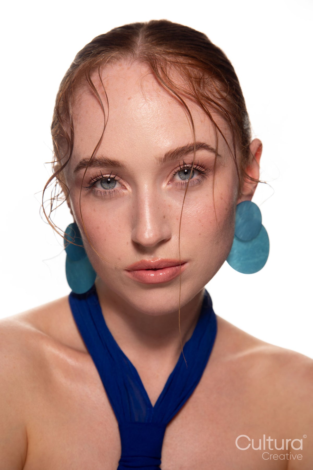 Studio portrait of a woman in a blue dress and large blue earrings
