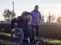 Smiling woman and man on wheelchair in field
