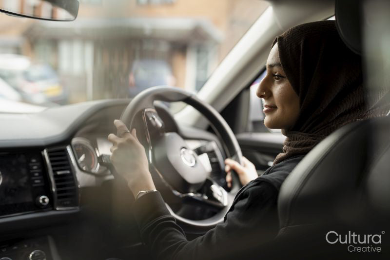 Young woman wearing hijab driving car