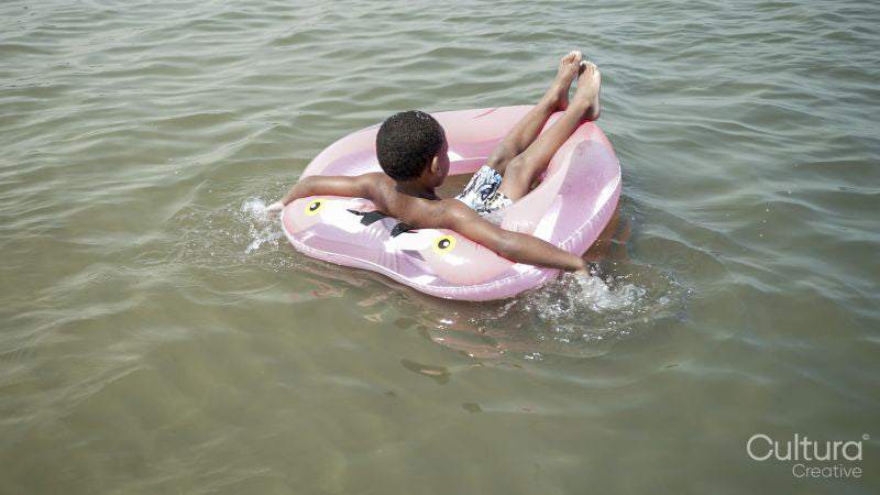 Rear view of boy floating on sea in inflatable ring