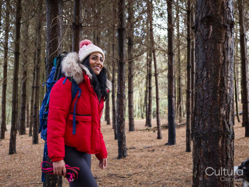 Female backpacker hiking in forest with dog