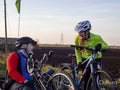 Disabled man on handcycle and woman with bicycle laughing in rural landscape