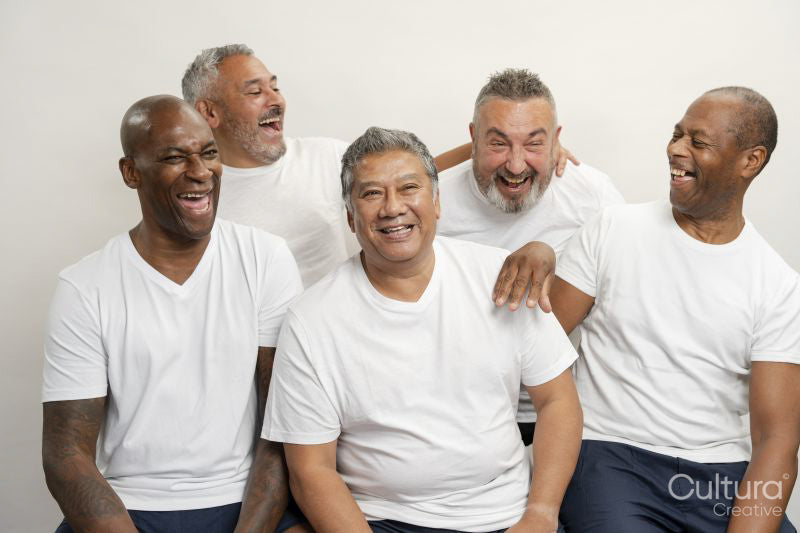 Group portrait of senior men in white t-shirts laughing against gray background