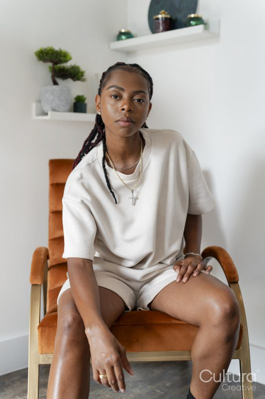 Portrait of beautiful woman looking at camera while sitting in armchair at home