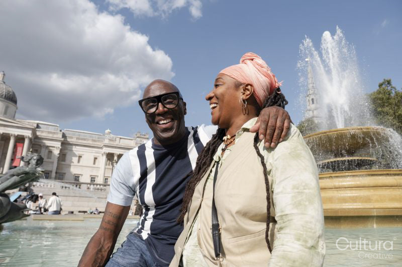 Happy mature couple posing next to fountain in Trafalgar Square