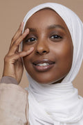 Studio portrait of young woman in white hijab touching face