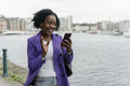 Smiling woman using smart phone by river