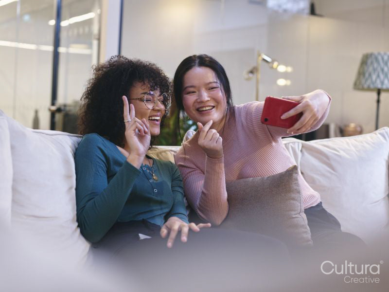 Two female coworkers taking selfie in modern office lobby