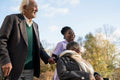 Senior people accompanied by nurse going on walk in park