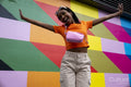 Smiling young woman jumping against colorful wall