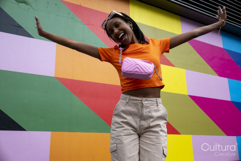 Smiling young woman jumping against colorful wall