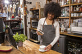 Smiling cafe owner sprinkling coffee with cinnamon