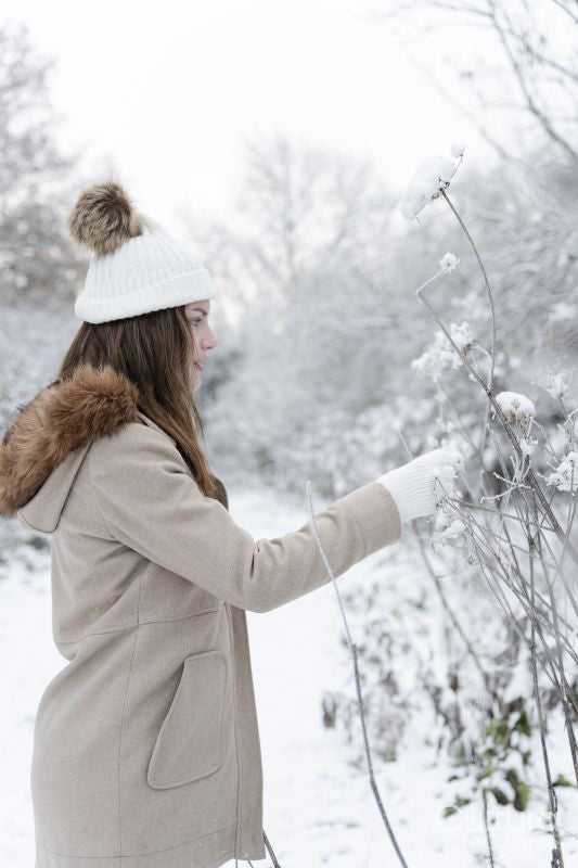 Woman touching dried plants covered with snow