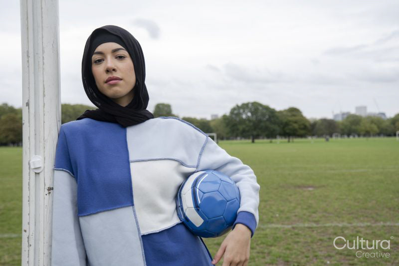 Portrait of woman in hijab standing in soccer field with soccer ball