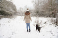 Rear view of woman walking with dog in snow covered landscape