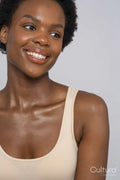 Studio portrait of smiling woman in cream colored tank top