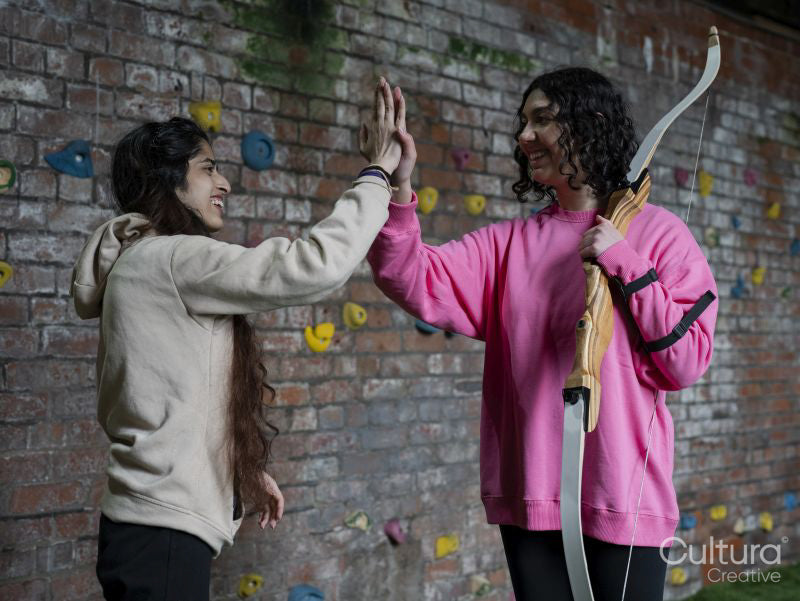 Young women doing high five during archery training