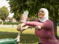 Sutton,Smiling woman in headscarf resting at park gym
