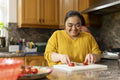 Smiling woman with down syndrome cutting tomato in kitchen