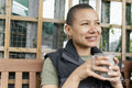 Portrait of smiling woman holding metal mug in urban garden