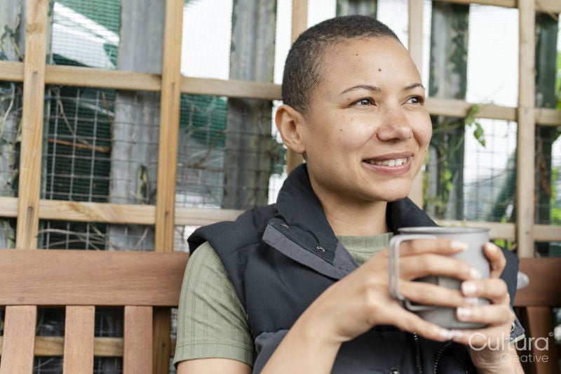 Portrait of smiling woman holding metal mug in urban garden