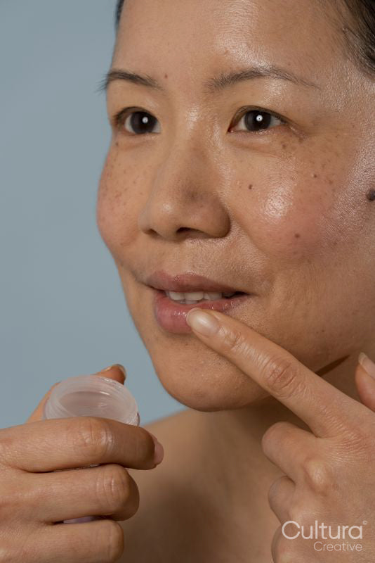 Mid adult woman applying lip balm