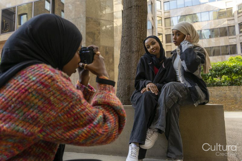 Young woman photographing friends wearing hijabs in city